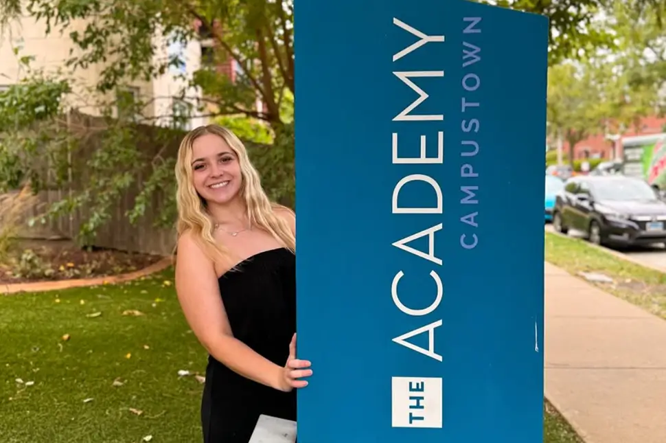 young woman standing in front of property signage